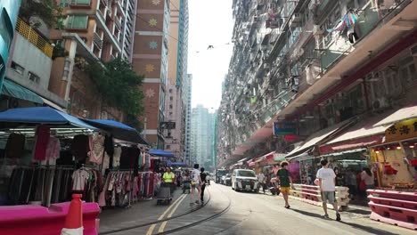 timelapse view of busy street view on chun yeung street, hong kong, showcasing bustling market stalls and vibrant urban life under a sunny sky.