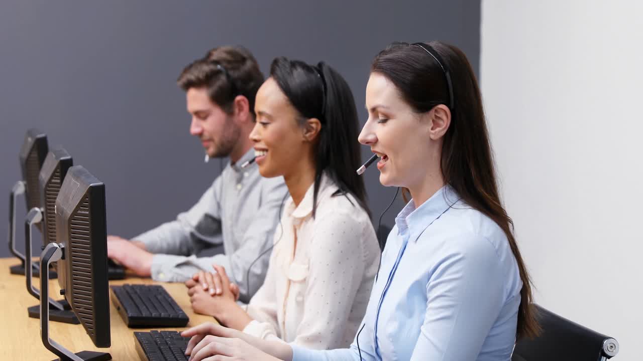 미소 짓는 고객 서비스 임원들이 4k 데스크에서 헤드 ⁇ 으로 이야기하고 있습니다.