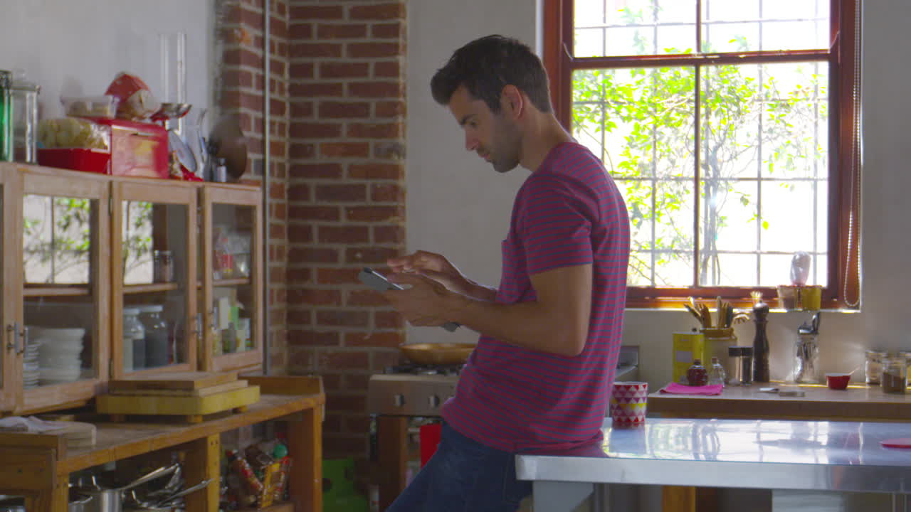 un joven está usando una tableta en la cocina, filmado en r3d
