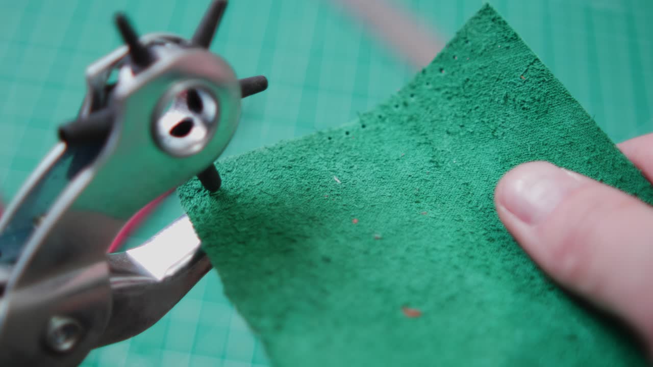 In a workshop, a man measures a piece of green leather carefully. He then cuts the leather while stepping on the scales to check his weight