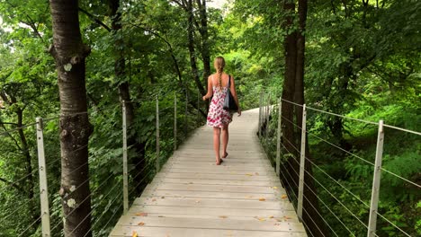 This-is-a-4k-clip-of-a-girl-walking-over-a-bridge-in-a-wood