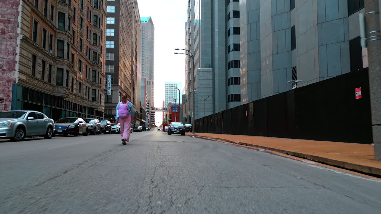 Saint Louis USA, 14 August 2025: Following a girl with a backpack strolling by the city. Low-angle view at the buildings of St. Louis, Missouri, USA