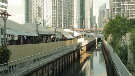 jodd fairs night market with canal alongside with city buildings in the background