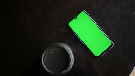 Take-away-paper-coffee-cup-and-smart-phone-with-green-screen-on-table-,