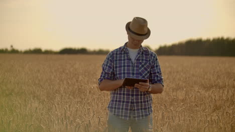 Stylish-old-caucasian-farmer-walking-in-the-golden-wheat-field-on-his-farm-during-the-morning-sunrise