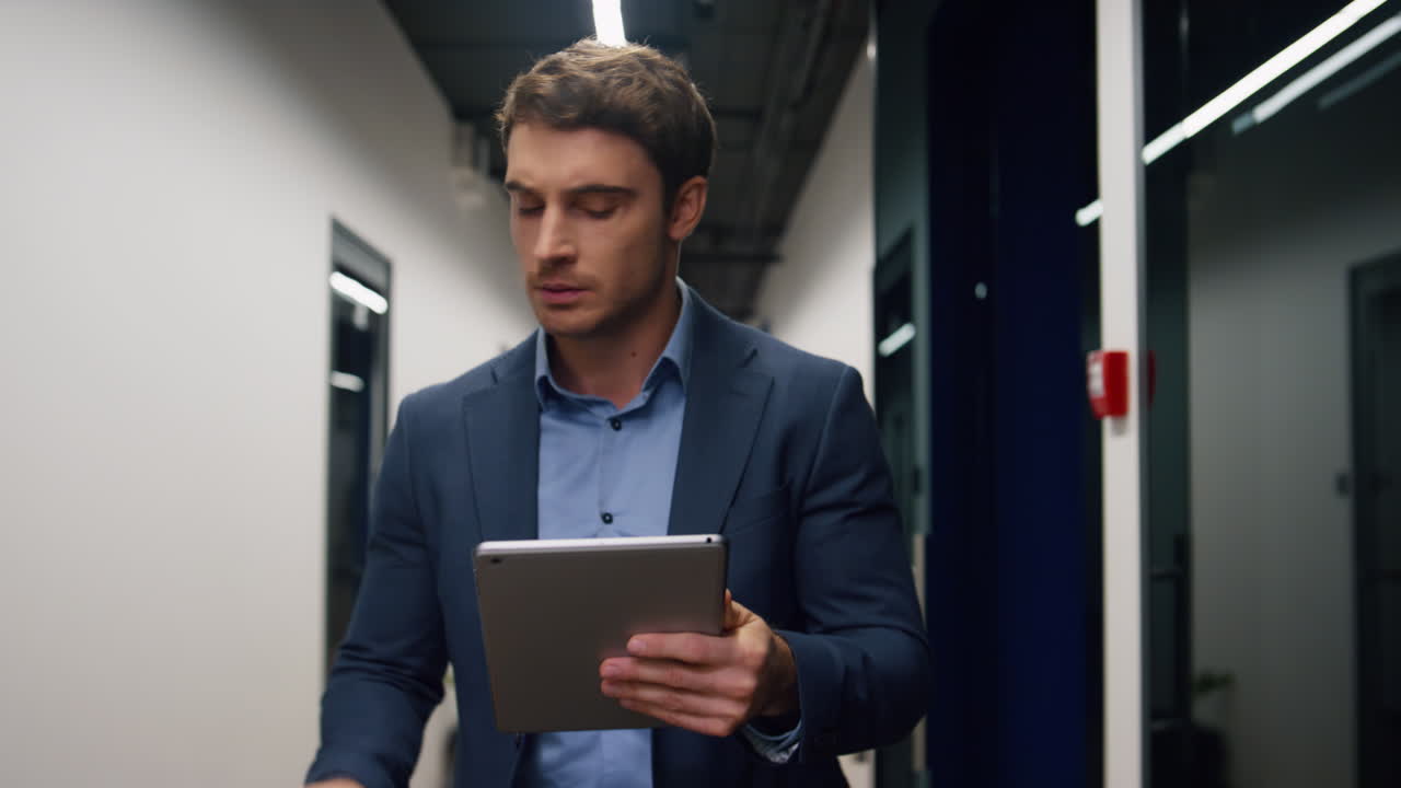 Smiling executive using tablet computer. Handsome man walking business center