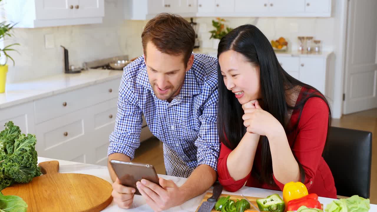 pareja usando una tableta digital en la cocina en casa 4k
