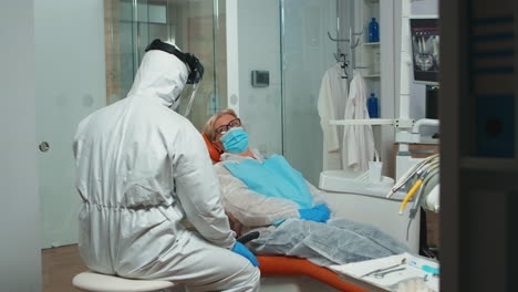 doctor in coverall showing to patient x-ray on stomatological monitor