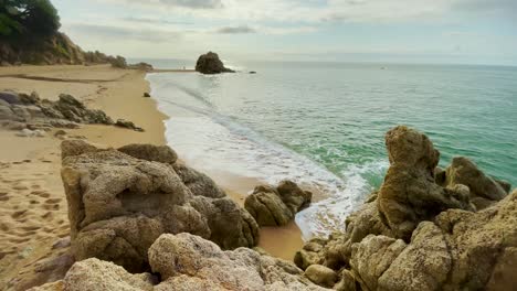 Mediterranean-beach-without-people-at-sunrise-turquoise-blue-calm-water-Barcelona-coast-Maresme-Costa-Brava-Spain-European-tourism-rocks