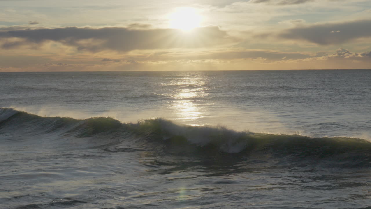 las olas se estrellan sobre un grupo de surfistas en la pintoresca hora dorada durante un impresionante amanecer