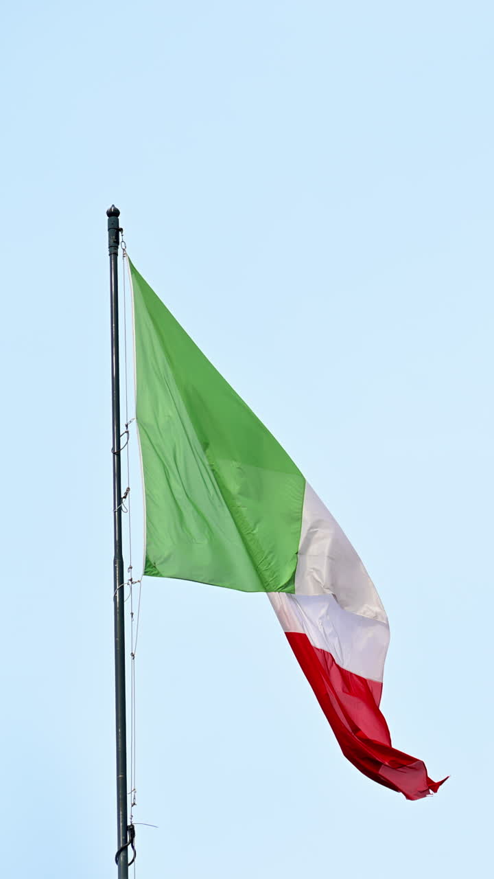 La bandiera italiana che sventola all'esterno su uno sfondo di cielo blu a Roma, Italia. Verticale