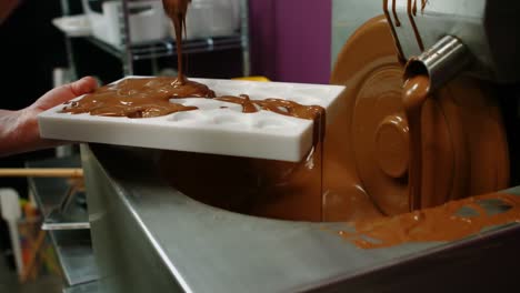 worker filling mould with melted chocolate