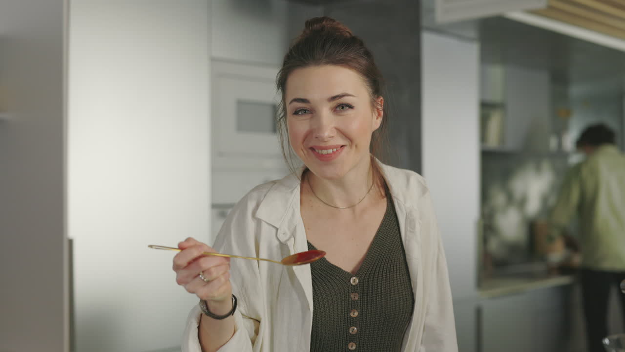 Woman Tasting and Enjoying Food in a Modern Kitchen