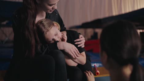 young girl smiles while sitting on the lap of a young woman