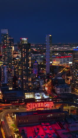 building of silvercup studios neighboring amazing modern architecture. lights of new york city at night aerial view. vertical video