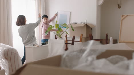 happy asian family moving into new home owners hanging picture decorating house together with children young couple enjoying real estate property investment with kids 4k footage