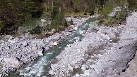 River-Flow-through-Mountain-Valley-surrounded-by-Forest-in-Austria,-Europe