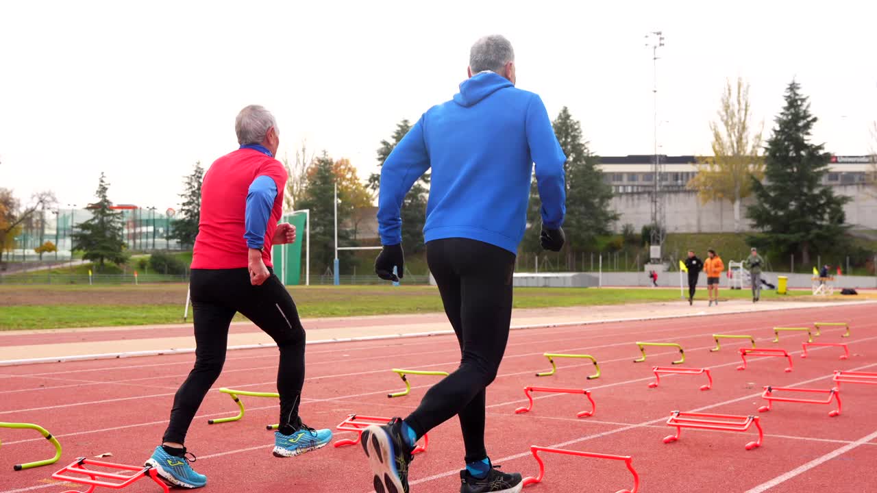 Men exercising on track with hurdles