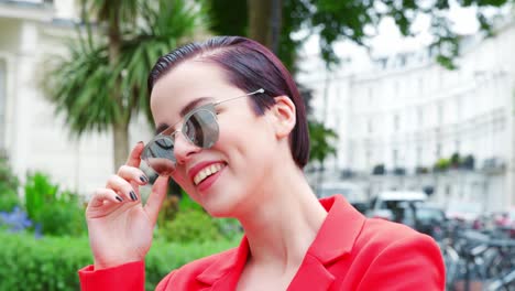 stylish woman wearing sunglasses standing on city street