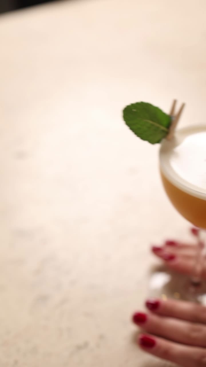 mujer sosteniendo un cóctel con guarnición de menta