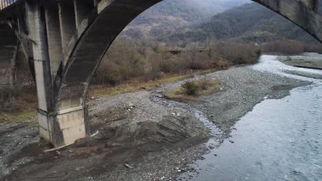 old concrete arch bridge over river in mountains