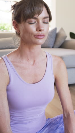 vertical video: caucasian woman sitting at home, eyes closed, light purple top