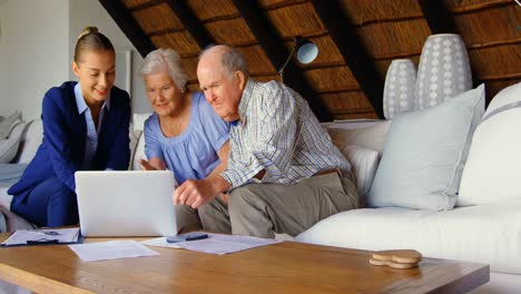 pareja de ancianos con un agente inmobiliario discutiendo sobre una computadora portátil en casa 4k