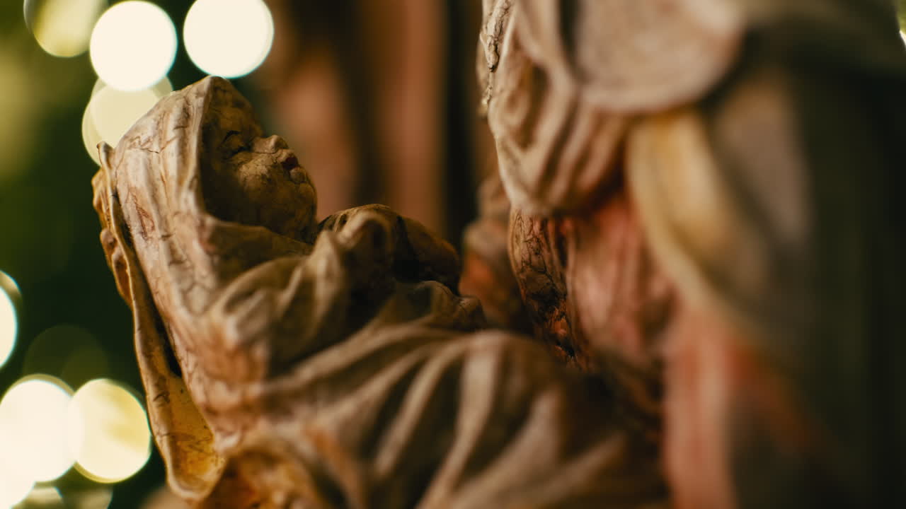 Detailed close-up of a Baby Jesus Nativity figurine in a manger against a background of warm glowing Christmas tree lights