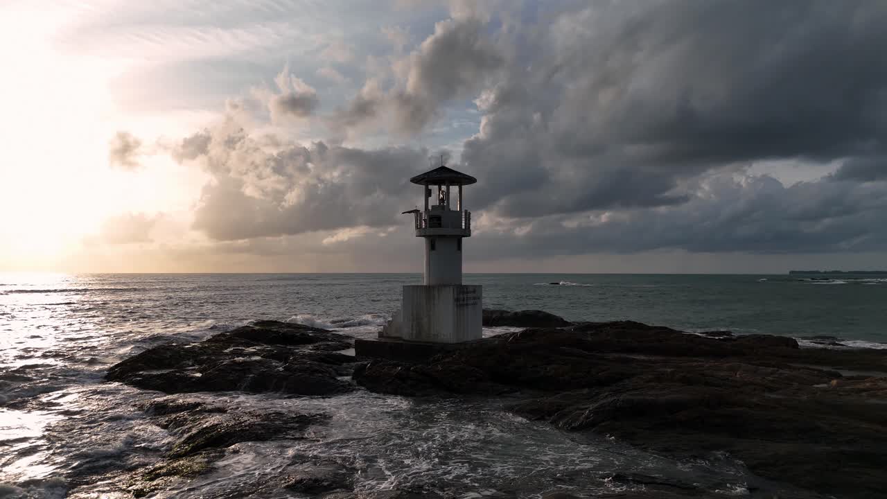 Lighthouse on rocky coast at sunset
