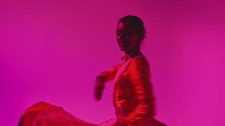 Waist Up Studio Shot Of Female Kathak Dancer Performing Dance Wearing Traditional Indian Dress Against Purple Background
