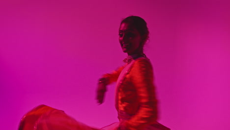 Waist-Up-Studio-Shot-Of-Female-Kathak-Dancer-Performing-Dance-Wearing-Traditional-Indian-Dress-Against-Purple-Background