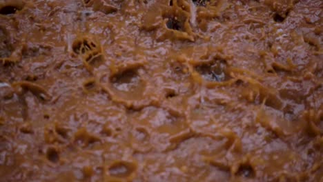 Cerrar-La-Toma-En-Cámara-Lenta-De-Fuertes-Lluvias-Cayendo-En-Un-Charco-Fangoso-Y-Creando-Salpicaduras