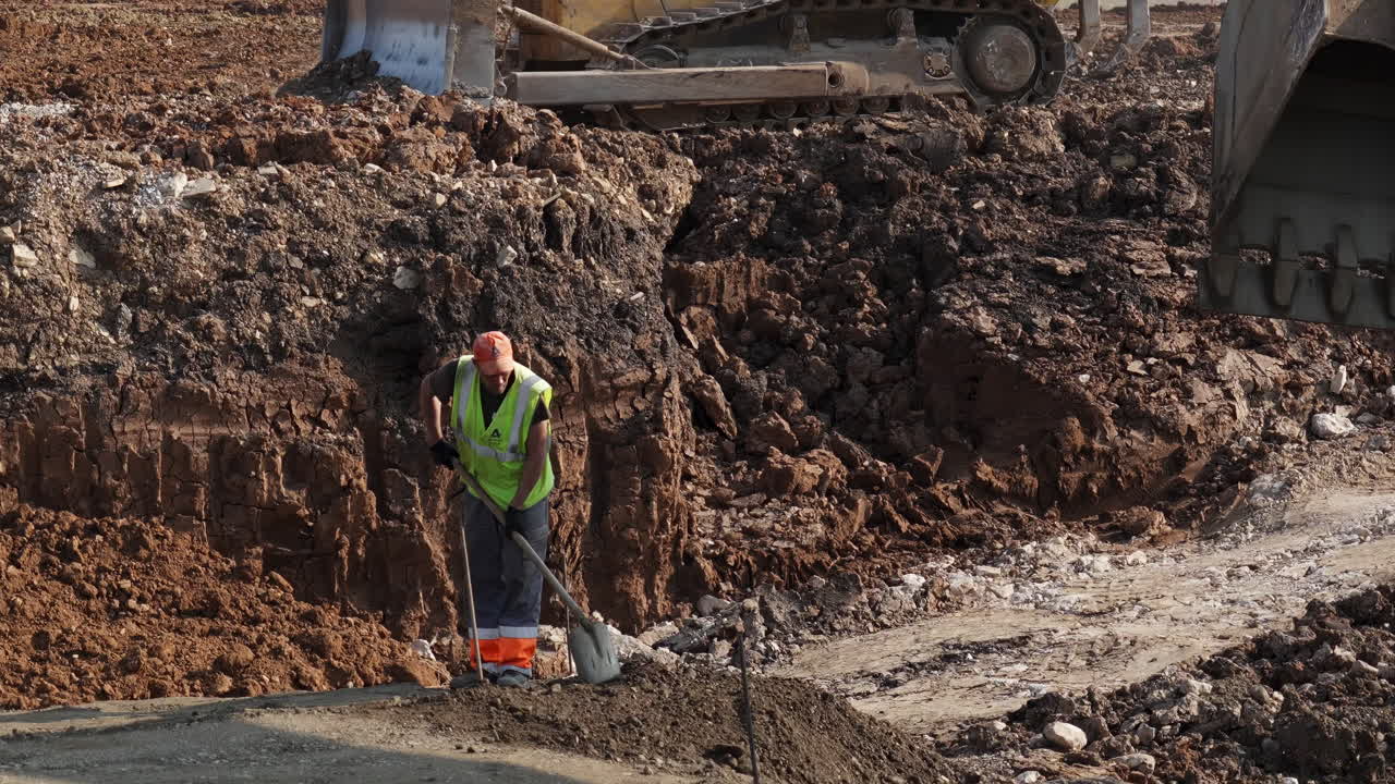 Construction Worker Shoveling Dirt on a Building Site