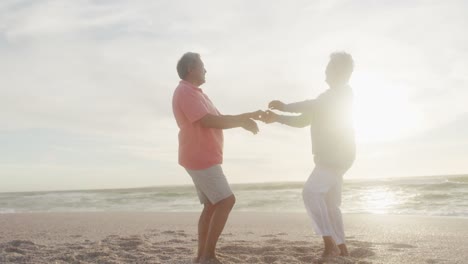 Glückliches-Hispanisches-Seniorenpaar,-Das-Bei-Sonnenuntergang-Am-Strand-Tanzt