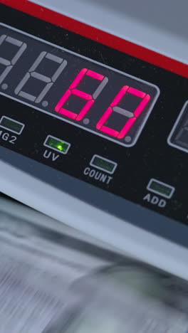 numbers growing quickly on the display of cash counting machine. american dollars being counted in equipment. close up. vertical video