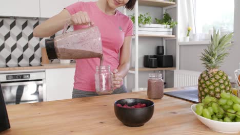 Parte-De-Una-Mujer-Vertiendo-Un-Frasco-De-Batido-En-La-Cocina