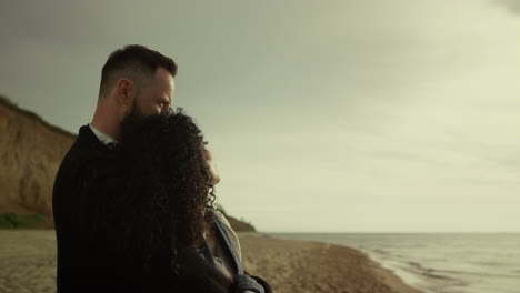 romantic couple hugging together on sea beach. two lovers enjoying date at coast