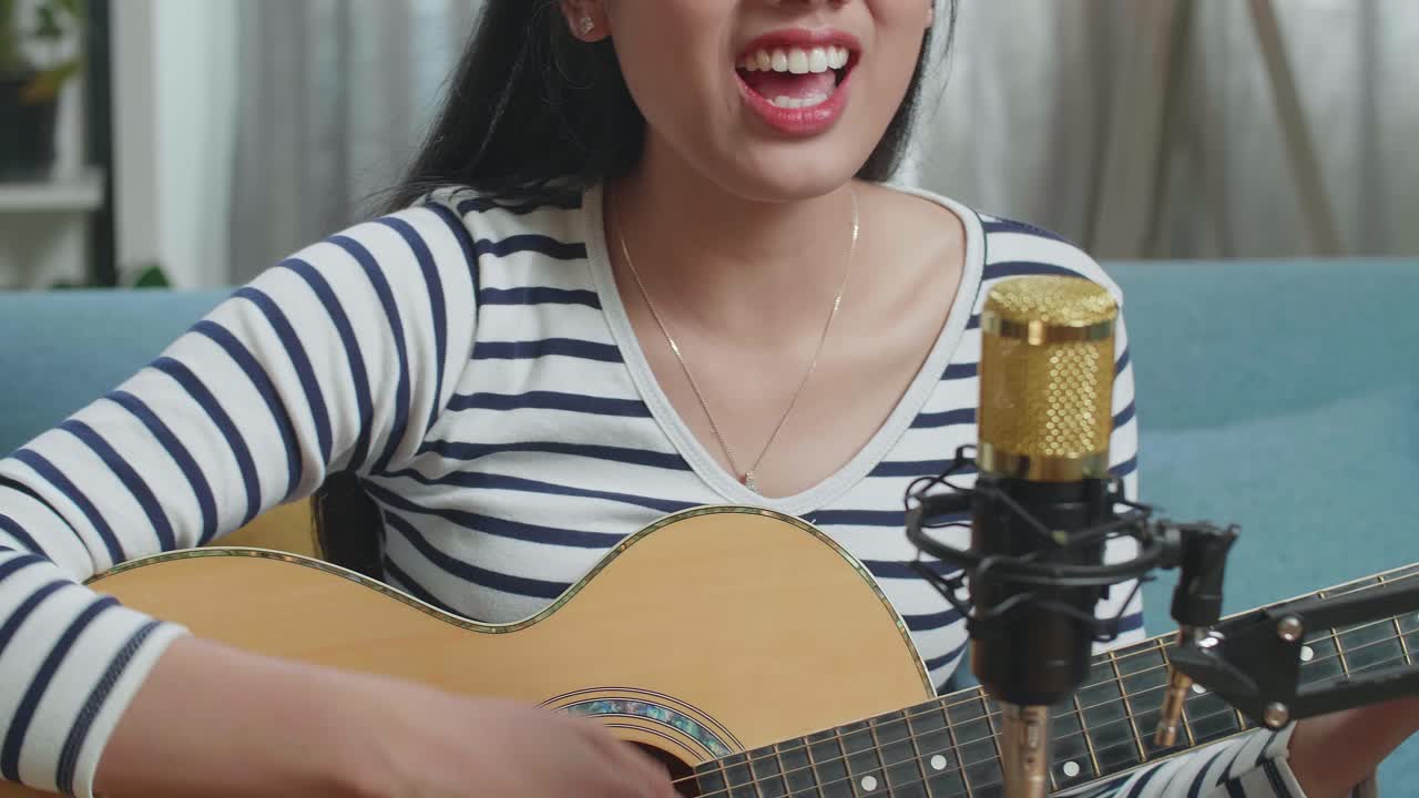 집에서 마이크를 들고 노래하고 기타를 연주하는 여자의 클로즈업