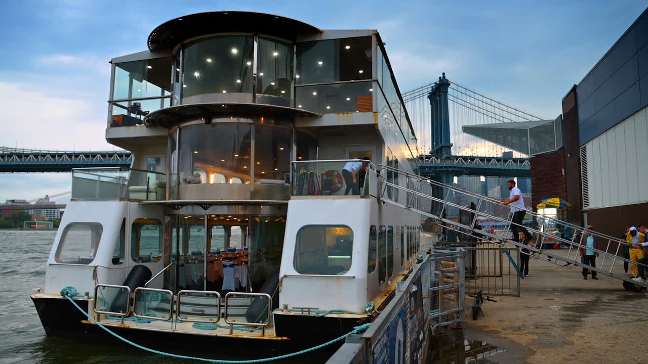 New York, USA, 1 August 2025: Passenger ship docked near Manhattan Bridge in New York. A large passenger ship prepares for boarding at the pier with the Manhattan Bridge in the background