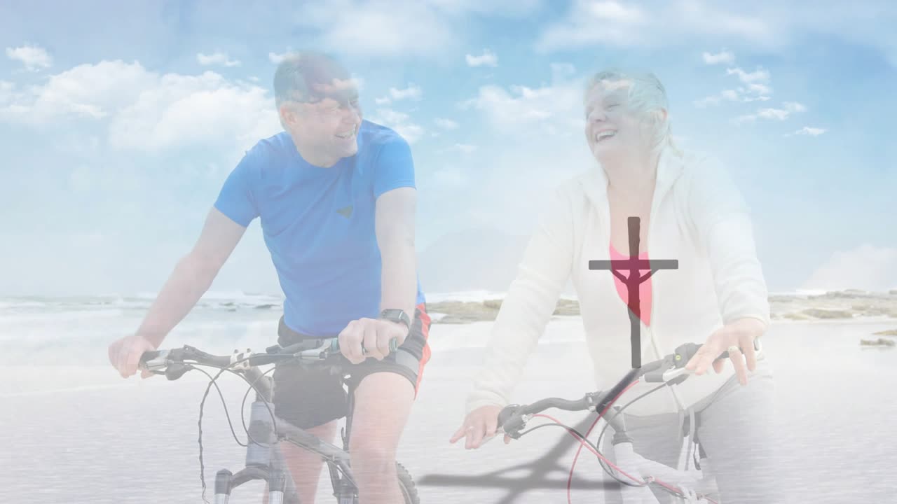 Starší pár jede na kole podél pláže po plynulém nástupu scény, s ikonou kříže propagující wellness.