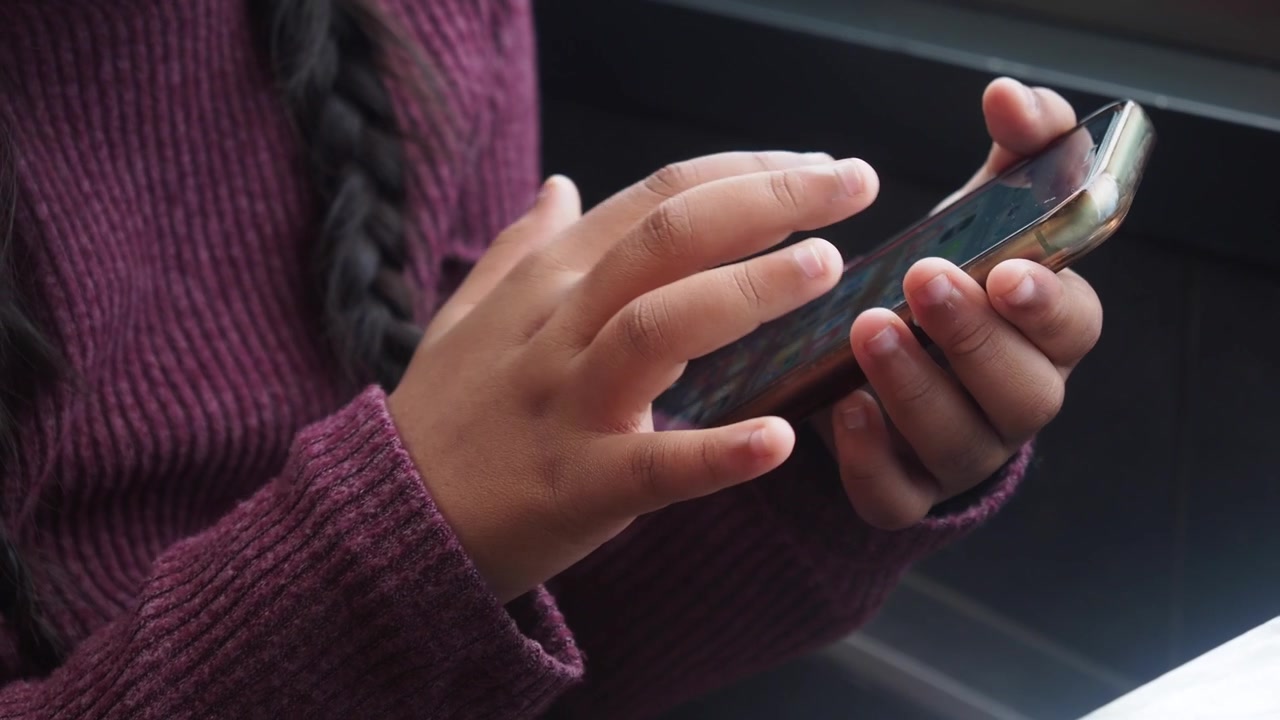 Primo piano: mani di bambino che toccano e scorrono su uno schermo di smartphone