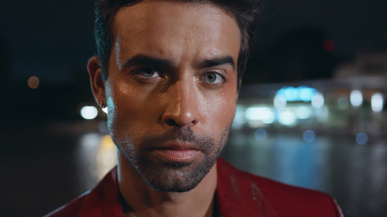 hombre seductor en primer plano mirando a la cámara con confianza en la ciudad nocturna. modelo masculino sexy