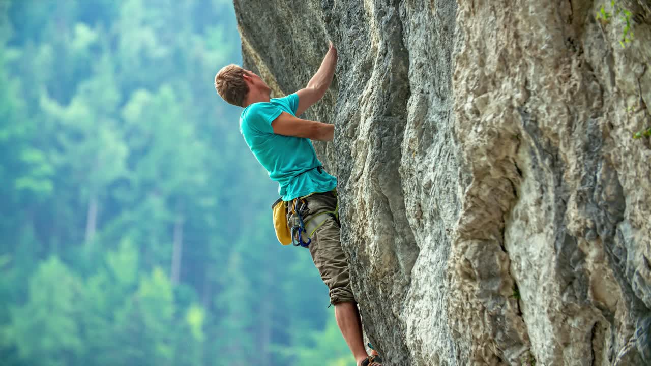 Zeitlupe einer professionellen Felskletterin, die an einer senkrechten Steinwand hängt