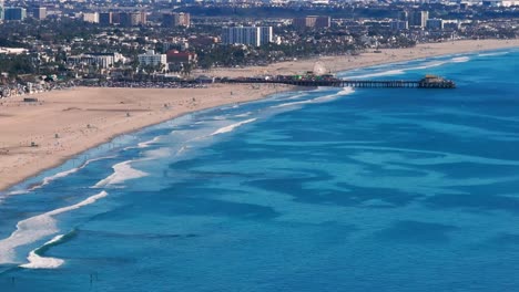 aerial drone shot looking down at the waves crashing on santa monica beach