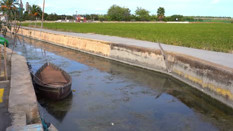 Empty-boat-in-shallow-canal-near-rice-field-in-Albufera,-Portugal