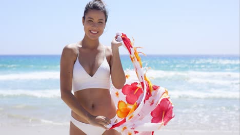 Young-woman-in-a-bikini-standing-on-a-beach