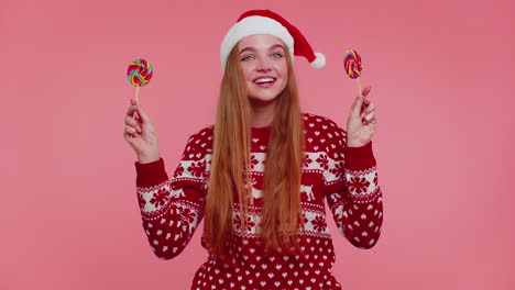 Funny-girl-in-New-Year-sweater-holding-candy-striped-lollipops-hiding-behind-them,-fooling-around