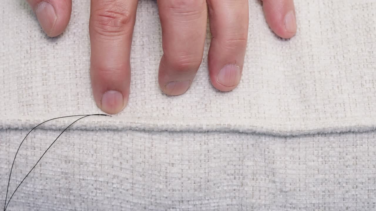 Hands push along freshly sewn pillow seam, testing finish and alignment