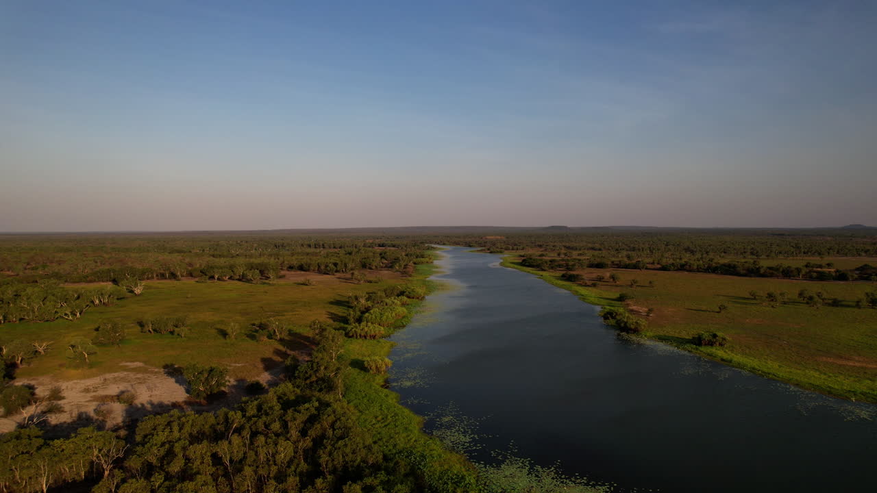 Vista aérea em movimento da terra em direção ao Mary River, perto do Couzens Lookout Campground, revelando as vastas planícies de inundação e a paisagem remota do Parque Nacional de Kakadu