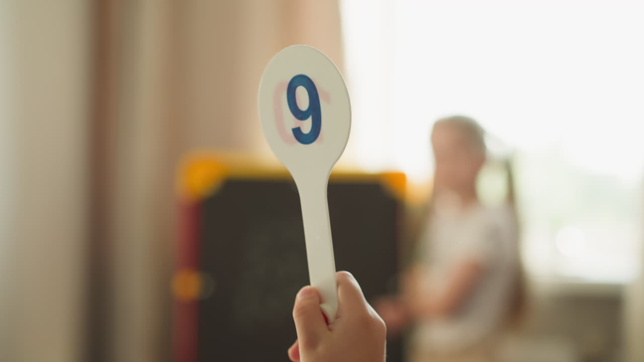 el escolar levanta la etiqueta con el dígito nueve y la niña resuelve las tareas